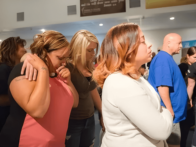Women praying together in community, supporting families through crisis