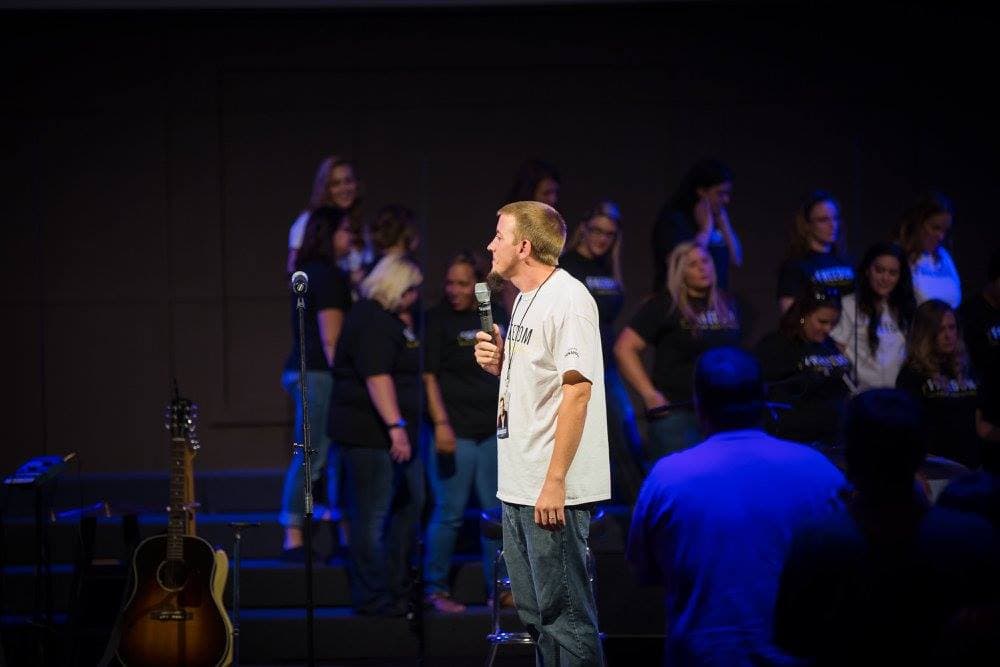 Young Justin in Freedom shirt holding microphone, sharing his testimony